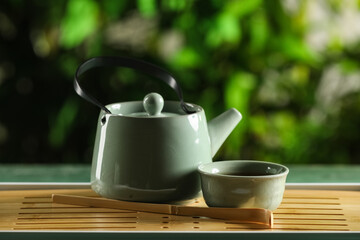 Tray with teapot and cup of hot tea on green grunge table outdoors