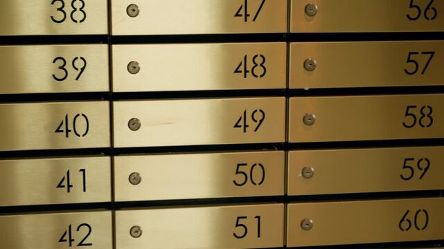 Golden metal vault wall lined with numbered safe deposit boxes in orderly rows, highlighting secure financial storage, sequential numbering, and polished brass compartments