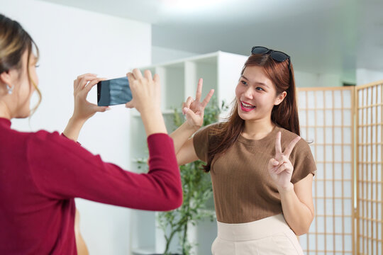 Capturing Memories. Young woman posing for a selfie while her friend takes a photo.