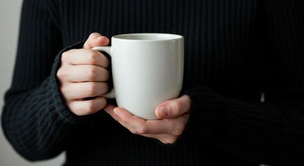 Person holding a blank white mug with both hands in a cozy dark aesthetic