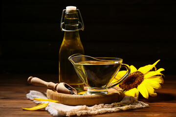 Tray, glass jug and bottle of sunflower oil on brown wooden background, closeup