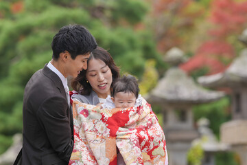 A man and woman are holding a baby and the baby is wrapped in a blanket. The scene is peaceful and loving, with the family enjoying each other's company