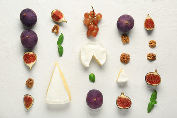Composition with pieces of tasty Camembert cheese, walnuts and fresh ripe figs on white background