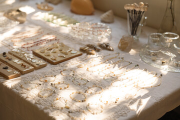 A collection of jewelry and decorative objects are displayed on a lace covered table
