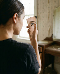 Contemplative woman gazes into cracked mirror shard