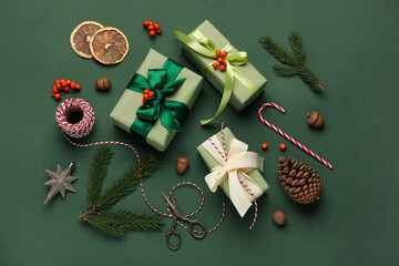 Christmas gift boxes with rope, scissors, fir tree branches and decor on green background
