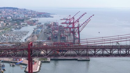 Side-on aerial drone shot of half marathon and 10K long-distance running event in Lisbon, Portugal. Runners crossing the iconic famous red 25th April suspension bridge, neutral grading