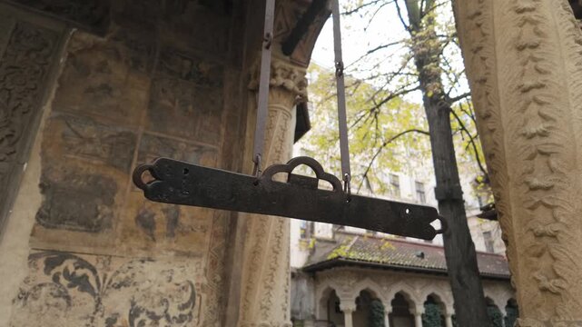 Ancient wooden semantron hanging beneath carved columns in the quiet monastery courtyard
