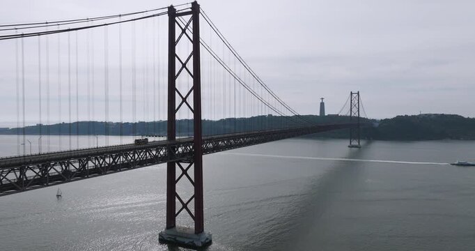 Aerial drone view of a pack of elite half marathon runners leading the race behind a patrol car on the red 25th April suspension bridge in Lisbon, Portugal