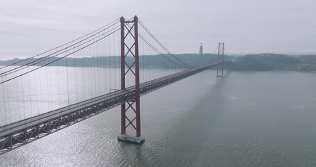 Cinematic aerial drone view of the empty red 25th April suspension bridge over the Tagus river in Lisbon, Portugal, with no cars or traffic before the running event