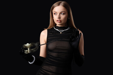 Beautiful young woman with carnival mask on dark background