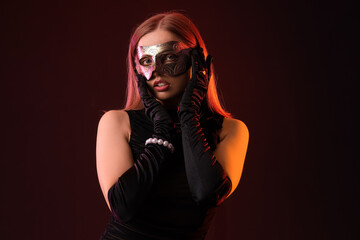 Beautiful young woman wearing carnival mask on dark background