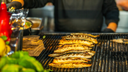 Chef grilling mackerel fish fillets on barbecue for traditional Istanbul street food sandwich Balik Ekmek. Turkish cuisine concept