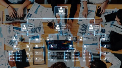 A diverse team engages in a strategic business meeting, surrounded by charts and laptops, showcasing remote collaboration and data analysis in a modern office setting. Raster - Powered by Adobe