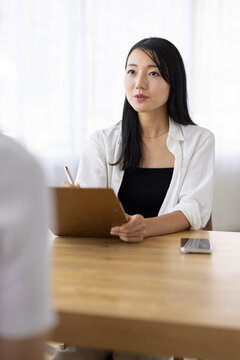 Woman Taking Notes During a Conversation at Work
