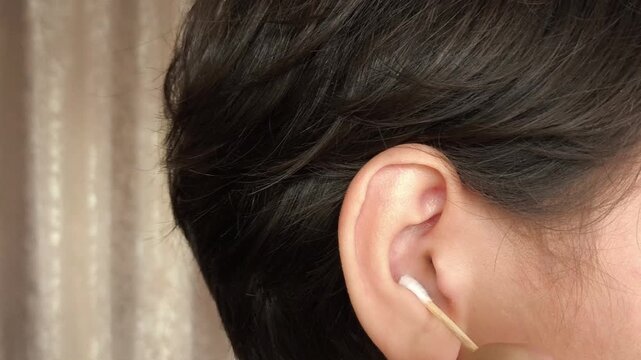 Teenage boy cleaning ear with cotton swab close-up. Wooden cotton buds. Hygiene