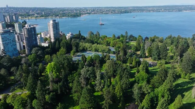 Drone Push Over Stanley Park Forest Revealing English Bay, Downtown Vancouver High-Rise Towers, Waterfront Parkland, and Coastal Urban Views