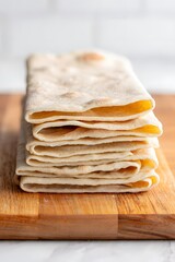 Freshly made tortillas stacked on a wooden board ready to be used for a meal prep