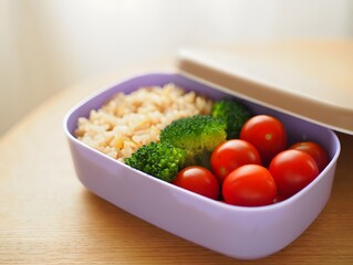 Healthy lunchbox with rice broccoli and tomatoes on a wooden surface in daylight