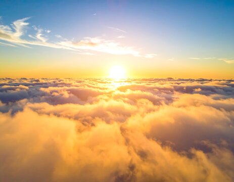Aerial view of a radiant sunrise above a sea of fluffy clouds