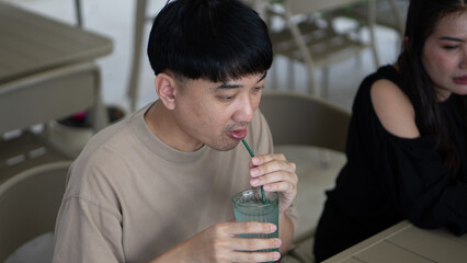 Man having lunch with a woman at an outdoor cafe, eating and drinking together in a relaxed setting.