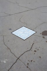 Square tile inlay on cracked concrete ground surface viewed from above outdoors