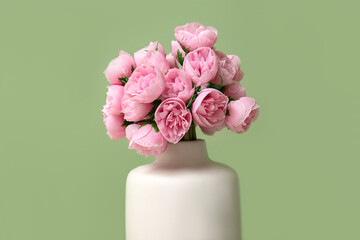 Vase with pink artificial flowers on green background, closeup