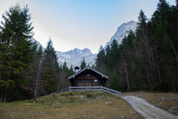 Rustic wooden cabin nestled in a serene forest landscape surrounded by towering mountains, showcasing natural beauty and tranquility in a peaceful outdoor setting