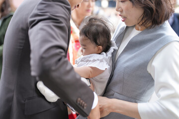 Obraz premium A man is holding a baby in his arms. The baby is wearing a white outfit