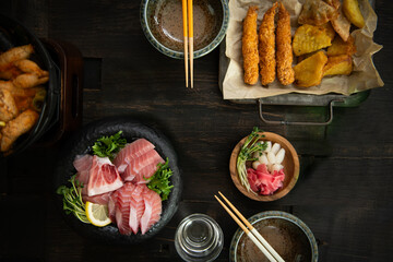 A delicious spread of Japanese cuisine featuring sashimi, fried shrimp, and hot pot on a wooden table
