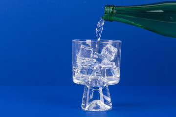 Pouring Refreshing Drink into a Glass with Ice Cubes