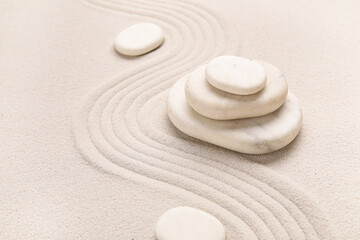 Composition with stack of spa stones and lines on light sand as background, closeup. Zen concept