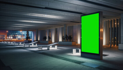 Illuminated green screen billboard in a modern urban environment at night, ready for digital content insertion