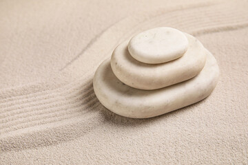 Composition with stack of spa stones and lines on sand as background, closeup. Zen concept
