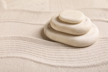 Composition with stack of spa stones and lines on sand as background, closeup. Zen concept