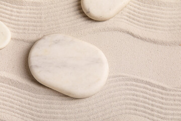 Composition with spa stones and lines on light sand as background, closeup. Zen concept