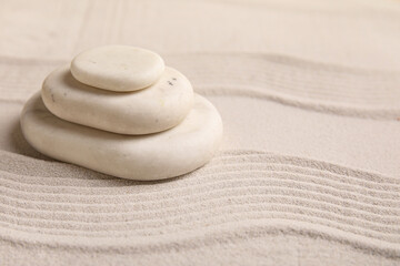 Composition with stack of spa stones and lines on sand as background, closeup. Zen concept