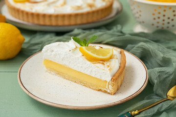 Plate with piece of tasty lemon pie on green wooden table, closeup