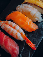 Close-Up of Assorted Nigiri Sushi on a Black Slate Plate: Tuna, Salmon, Shrimp, and Tamago, a Delicious Japanese Culinary Experience