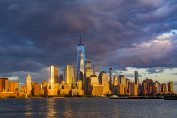 New York City with dark sky. New York City skyline with dramatic clouds. Manhattan skyscrapers in golden night at New York City. Iconic cityscape of lower Manhattan in New York City. NY panorama.