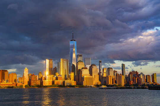 New York City with dark sky. New York City skyline with dramatic clouds. Manhattan skyscrapers in golden night at New York City. Iconic cityscape of lower Manhattan in New York City. NY panorama.