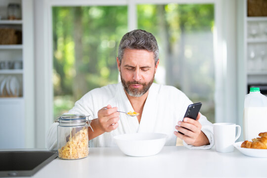 Mature Man eat breakfast in kitchen with fresh cereal and milk. Man eats healthy lunch enjoys a nutritious salad and vegetables at home. Tasty snack at kitchen table. Nutritious meal healthy food. - Powered by Adobe