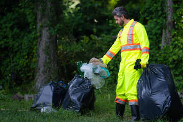 Volunteer in rubber gloves with trash bag clean up garbage on forest outdoor. Eco, environment conservation. Recycle pollution. Man collecting garbage and plastic trash. Save environment.