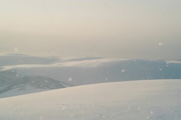 Dreamy snow falling gently over rolling hills creating a peaceful winter scene, perfect for holiday cards or a serene background, with soft hues and a calming feel