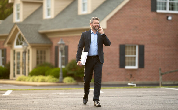 Real estate agent poses confidently in front of building ready for sale. Real estate entrepreneur closing deal. Real estate agent buying house. Realtor shows apartment. Real estate agent near building