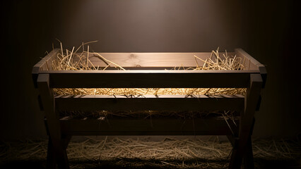 Empty wooden manger sits illuminated in dark stable awaiting baby Jesus on Christmas Eve, evoking peaceful anticipation.