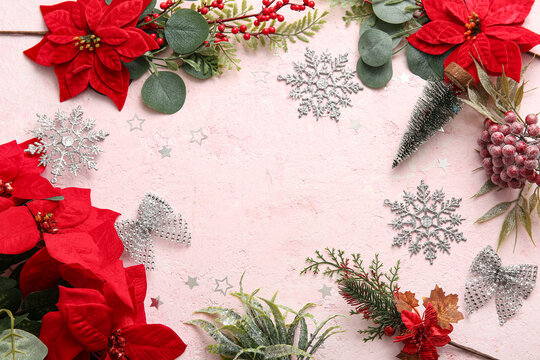 Frame made of Christmas poinsettia flowers and snowflakes on pink grunge background