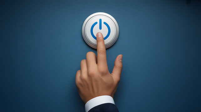 A hand pressing a white power button with a blue power symbol on a dark blue background surface
