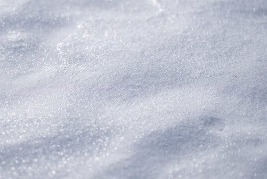 Frozen snow field in natural light. White snow backdrop with cold pattern. Minimal clean winter background. Frozen surface with snow and frost texture.