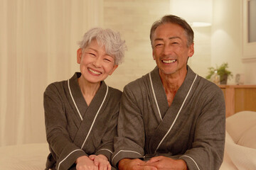 シニアの夫婦　ポートレート　夜のベッドルーム　カメラ目線